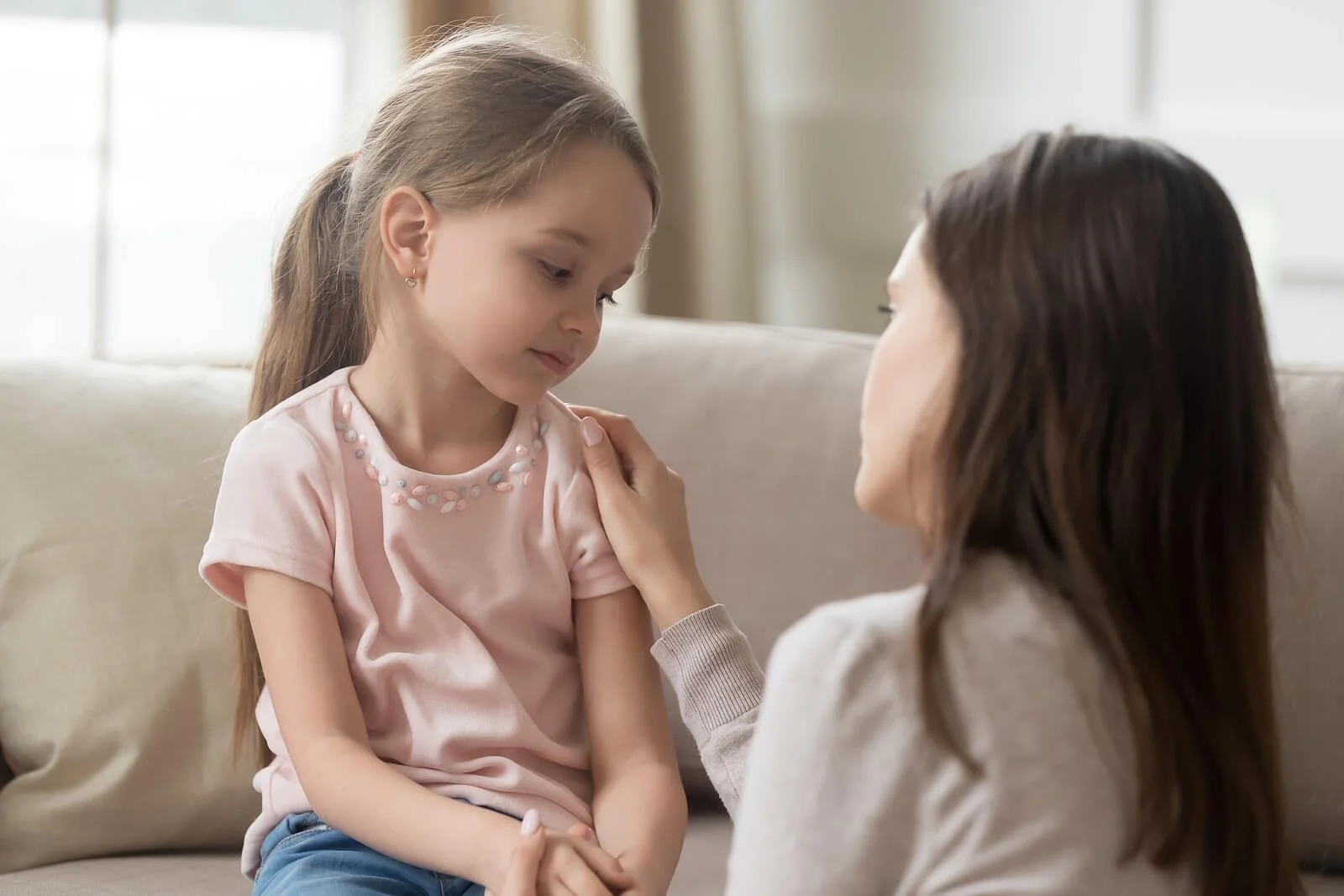 Parent speaking gently with a child while sitting together on a couch. Through child counseling in Columbia, MO, parents learn how to respond to anxiety with reassurance, understanding, and supportive communication.