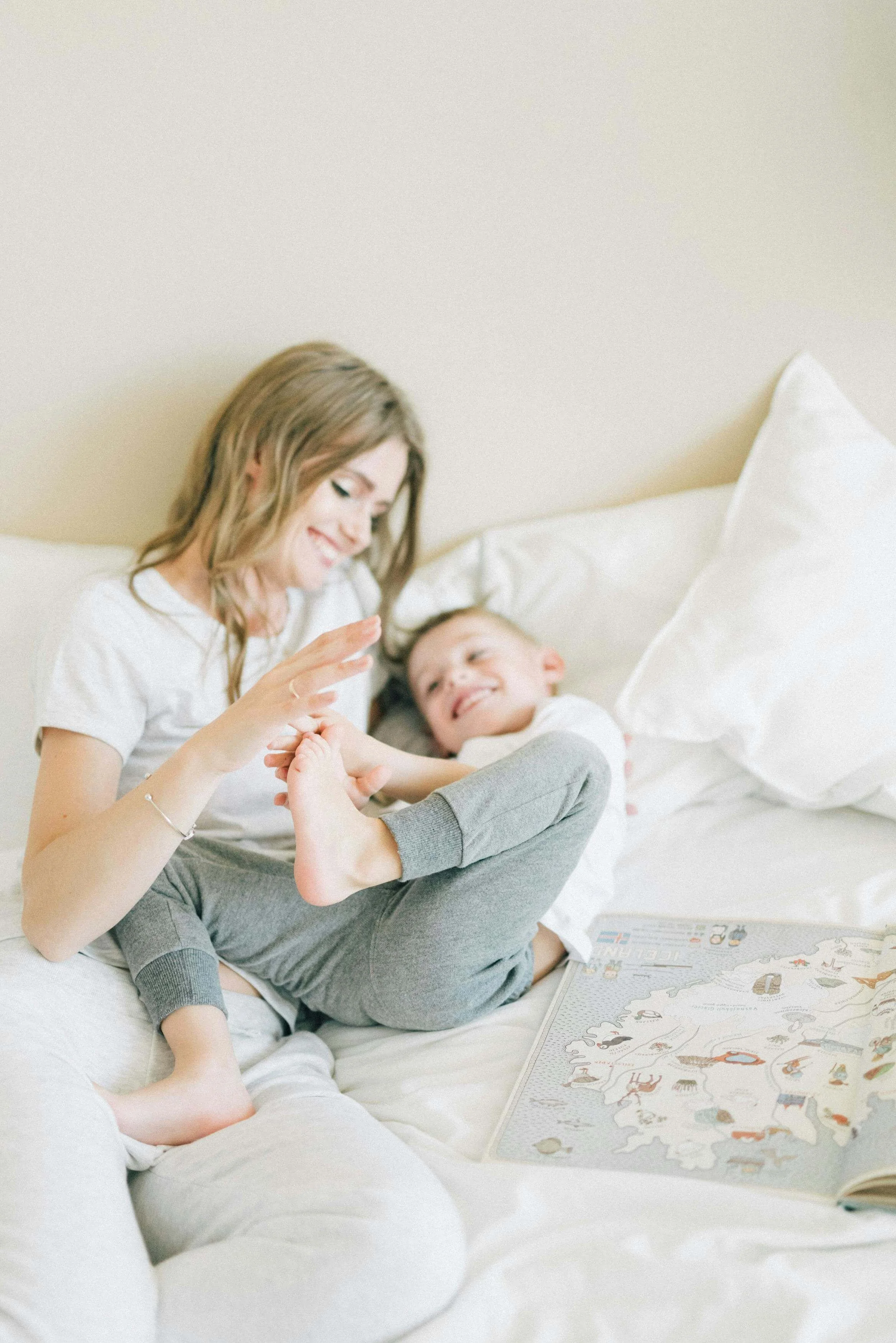Parent and child smiling together while relaxing on a bed at home. Child counseling in Columbia, MO helps anxious children build trust, confidence, and emotional regulation within the safety of their relationships.