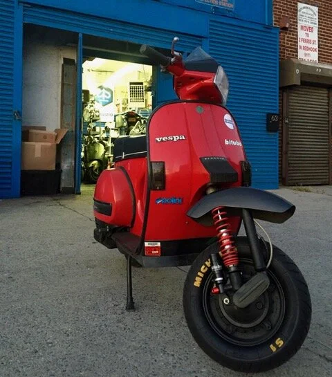 A restored vintage Vespa parked outside the shop