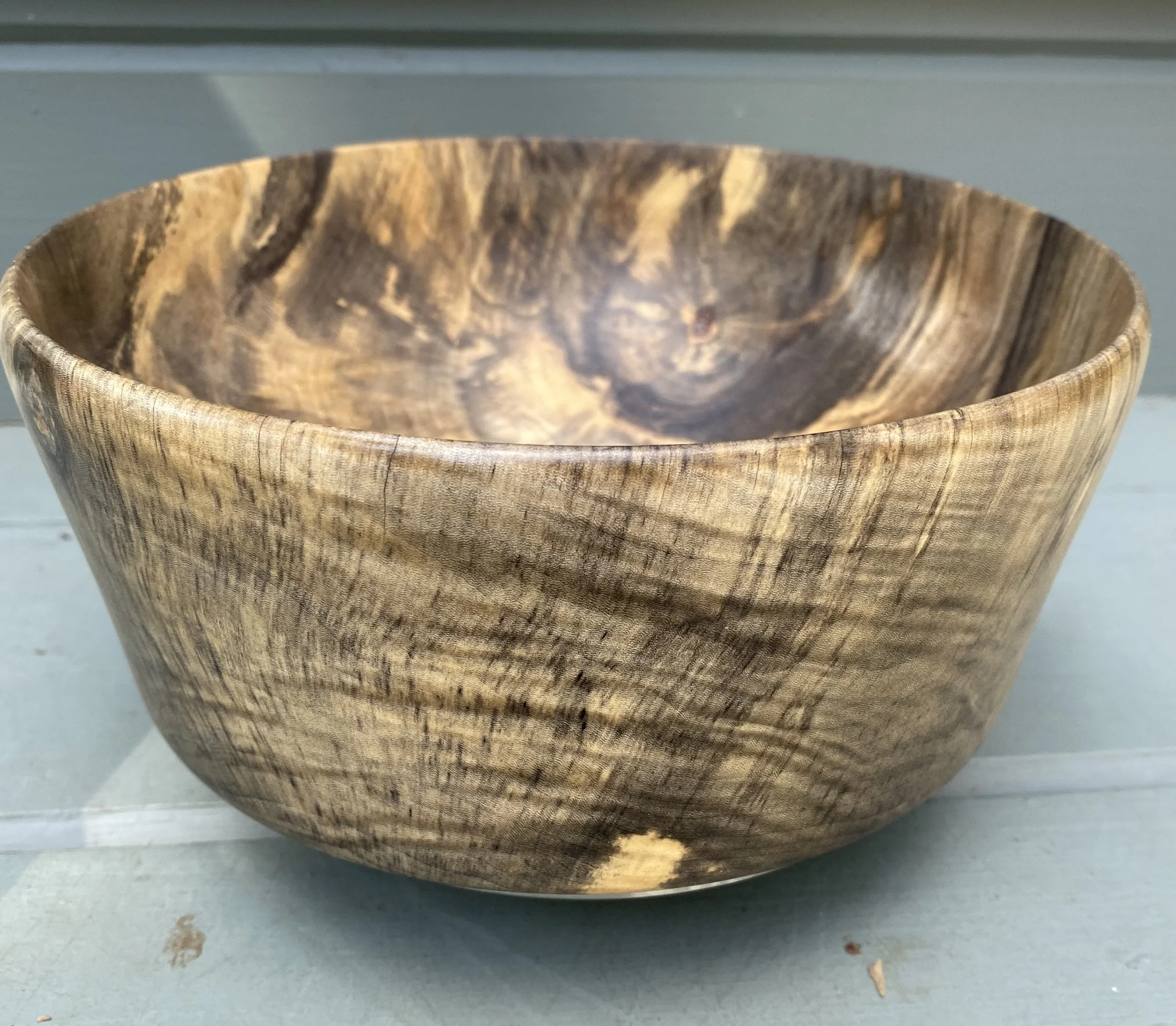 A handcrafted bowl turned from spalted pecan, showing dark lines and swirling grain patterns that highlight the natural character of the wood.