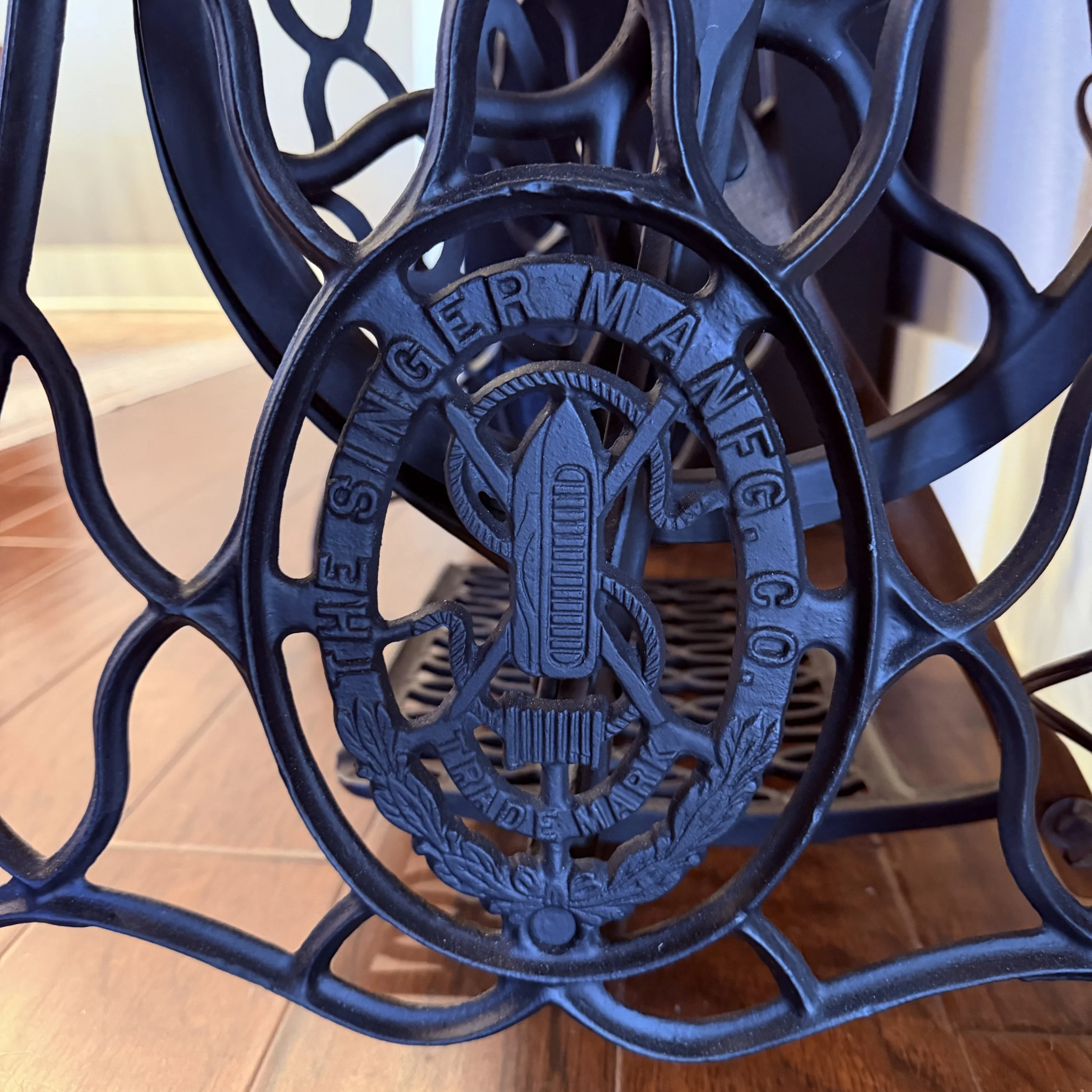 Close-up of restored Singer treadle sewing machine base badge and cast iron details