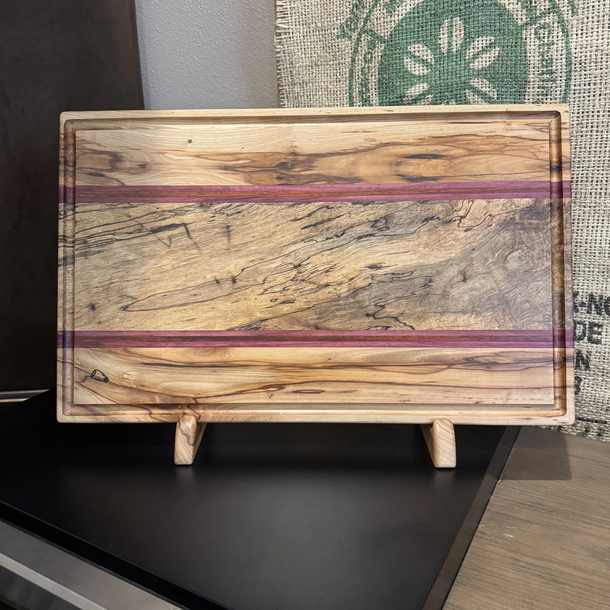 Cutting board featuring spalted pecan wood with vivid Purpleheart accent stripes.
