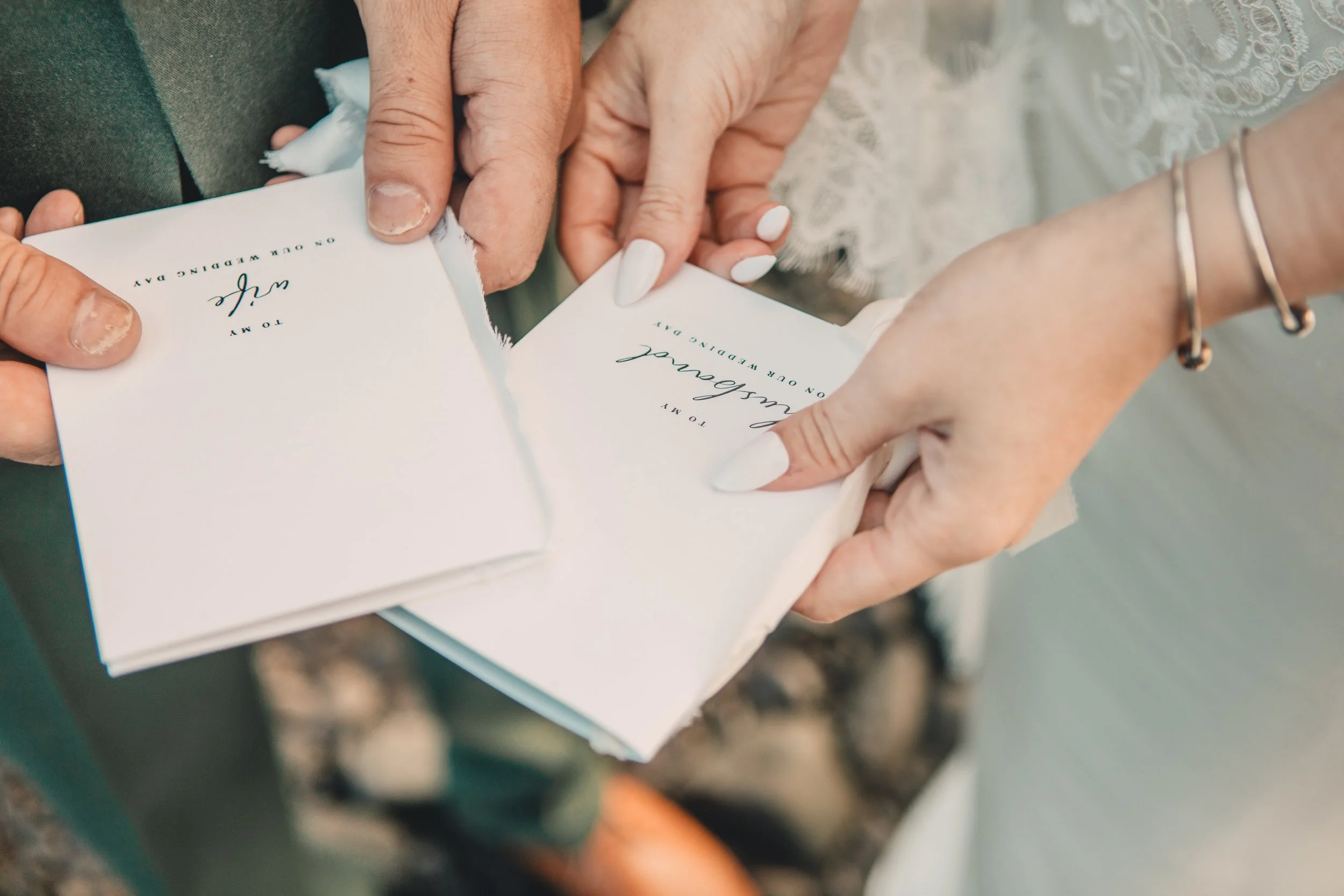 Close-up of hands holding torn wedding invitation card.
