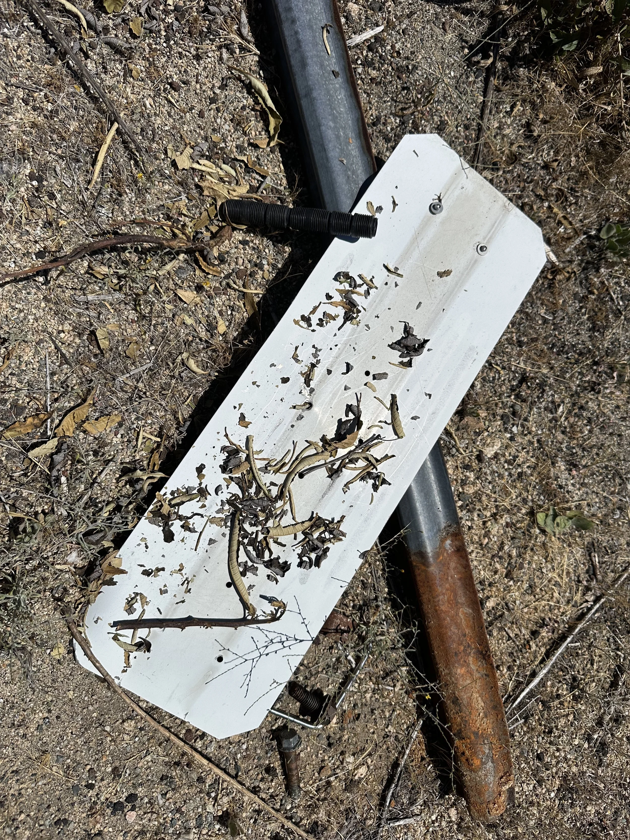 A road sign, sprinkler tube, sticks, and gravel.