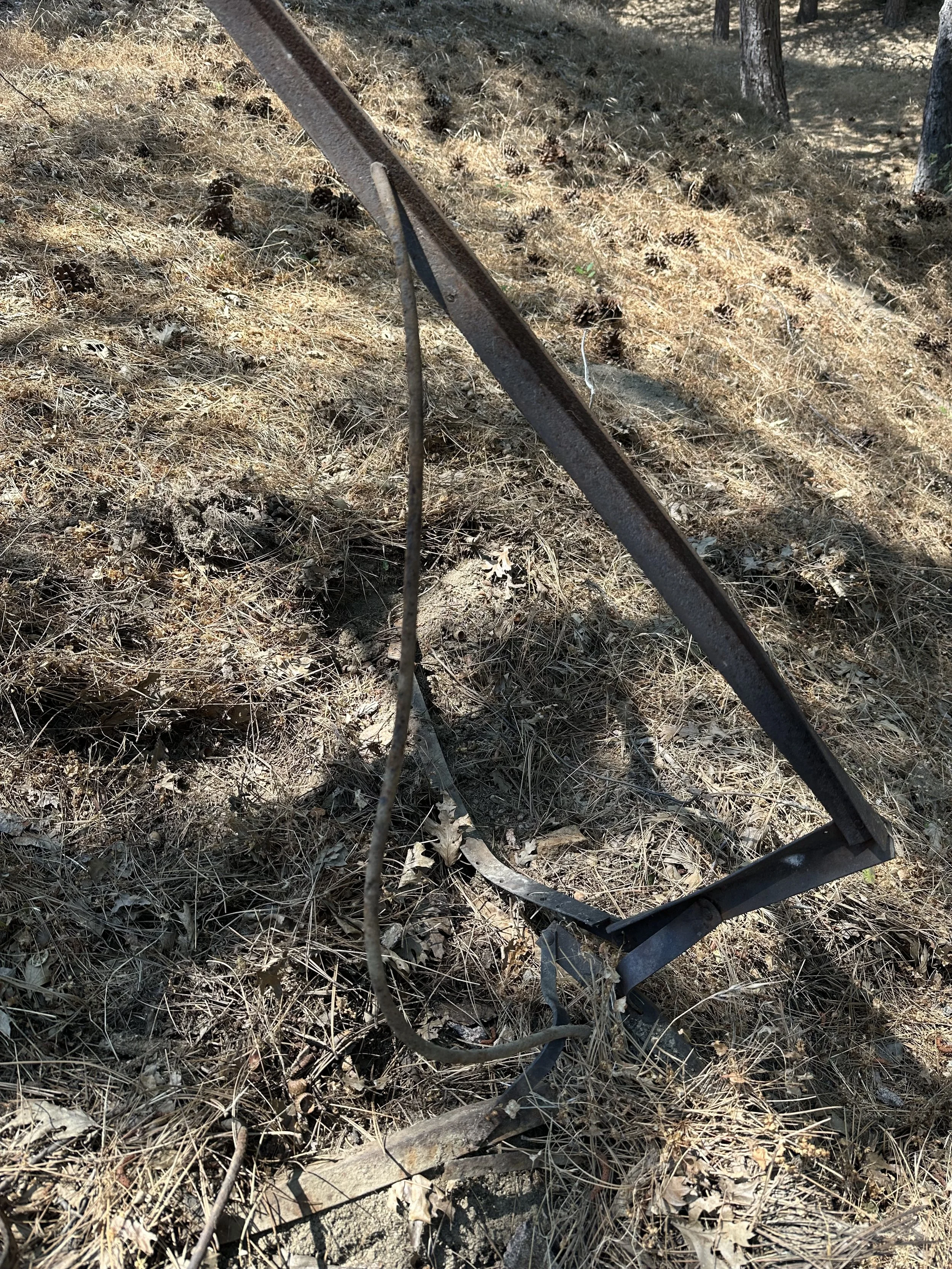 An arrangement of found rusty bars, wood and rocks in a field.