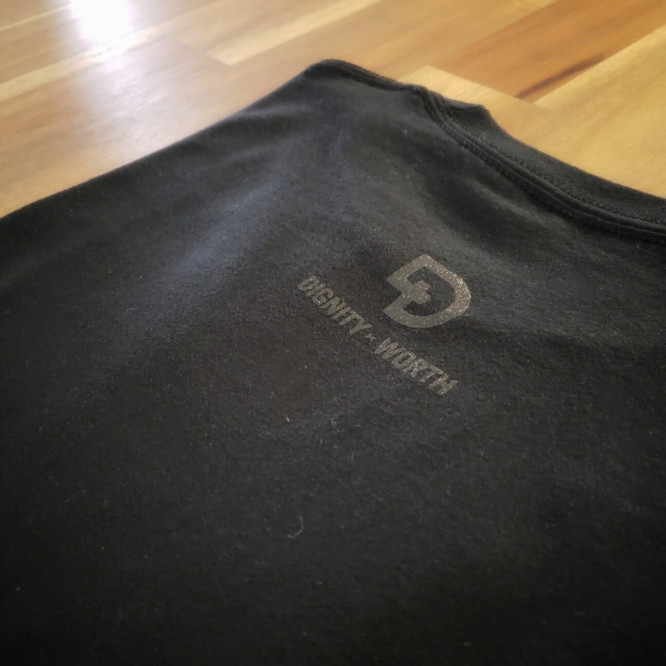 DIGNITY x WORTH black logo on back of black Justice shirt
