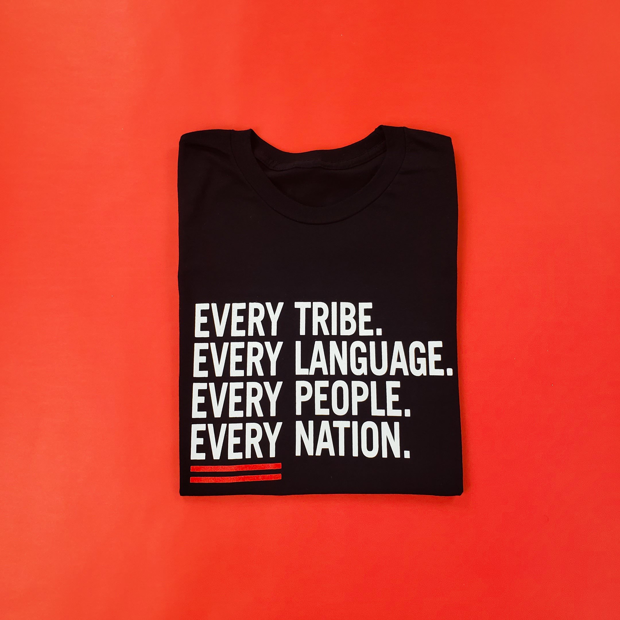 Black Every Tribe Shirt folded on red background
