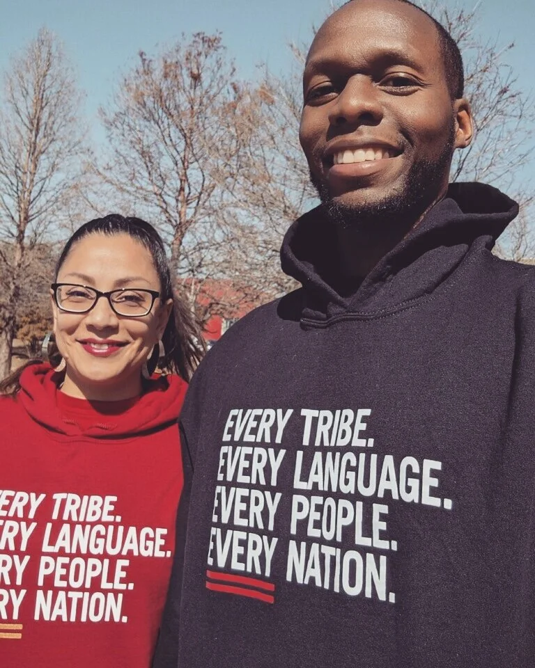 Two people smiling outdoors wearing hoodies with the text 'Every Tribe. Every Language. Every People. Every Nation.'