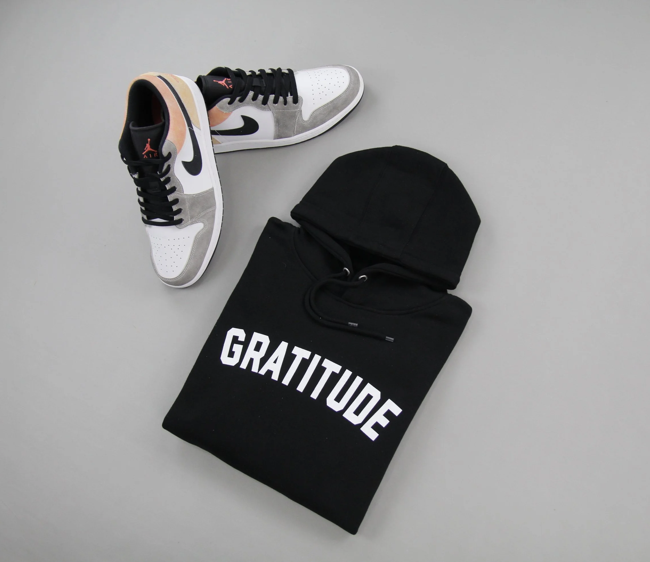 Front folded view of black GRATITUDE premium hoodie with colorful Air Jordan 1 shoes