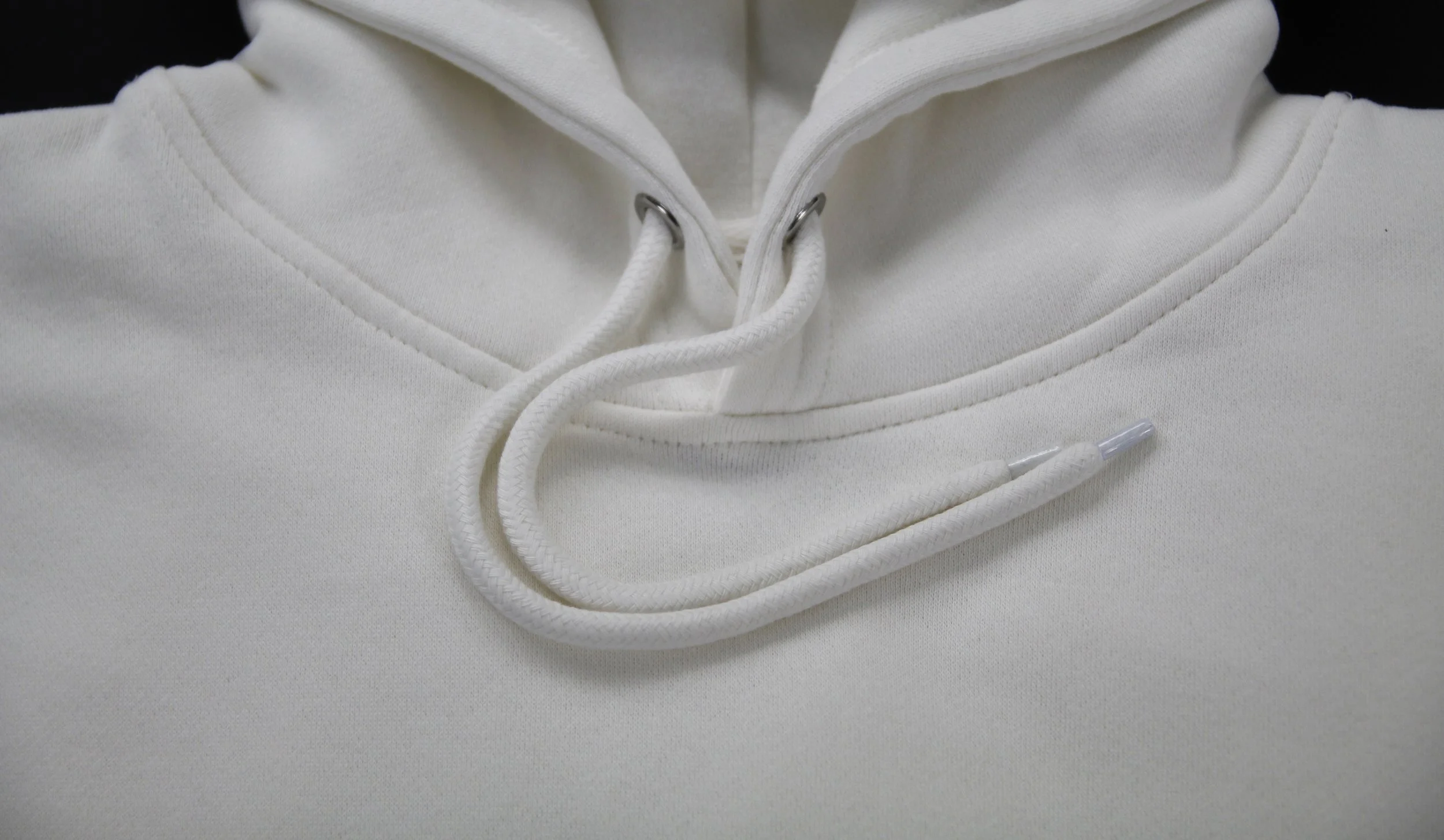 Off White Christian hoodie closeup shot of drawcords on black background
