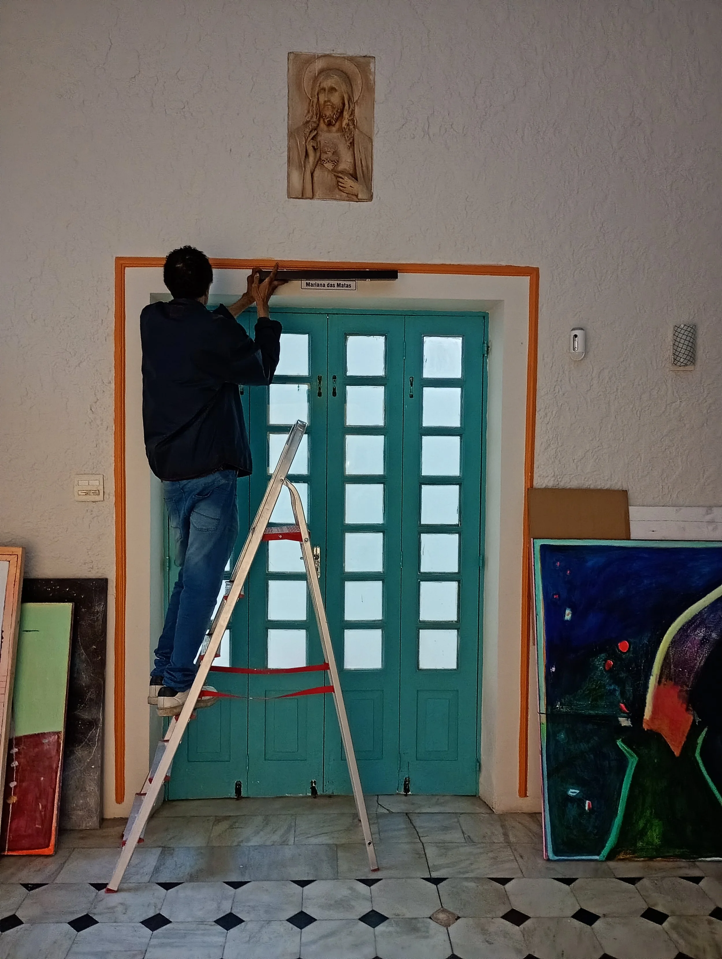  A ideia é colocar uma prateleira para quadros, na cor branca, que ficará invisível. No caso da foto testamos com a cor preta - que é a que tínhamos disponível - mas será branca e mais comprida.  (OBS: Os quadros no chão não são meus, são da Manô). 