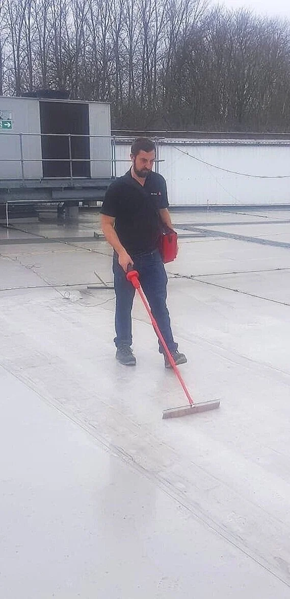 A man standing on a flat rooftop using a Buckleys dry leak detector .