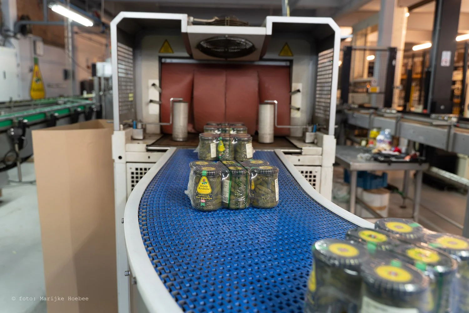 Blik op een verpakkingsmachine in een fabriek die potten augurken verwerkt, met potten op de lopende band.