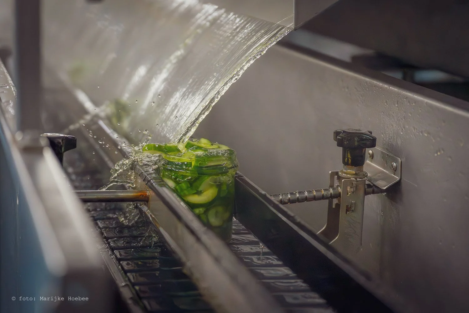 Groene gel met water die uit een spuit komt, gebruikt in een industriële productie.