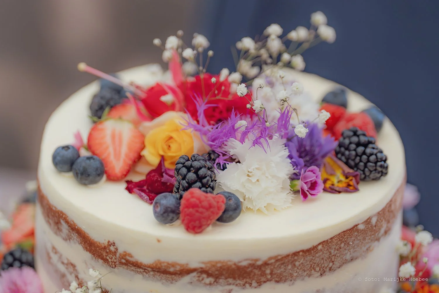 Taart versierd met bessen, aardbeien, bloemen en fruit