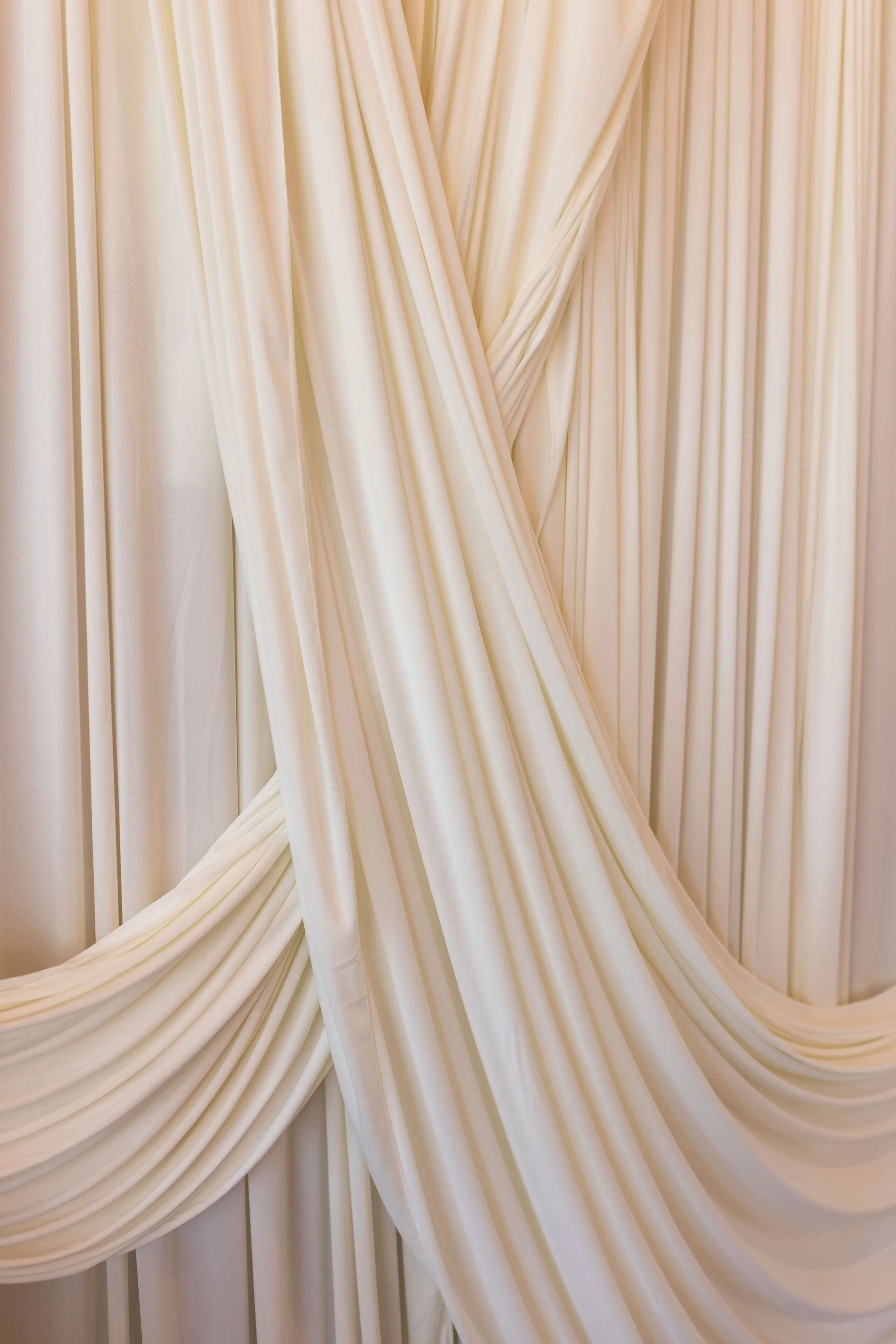 Cream-colored drapes or curtains gathered and twisted to create decorative folds.