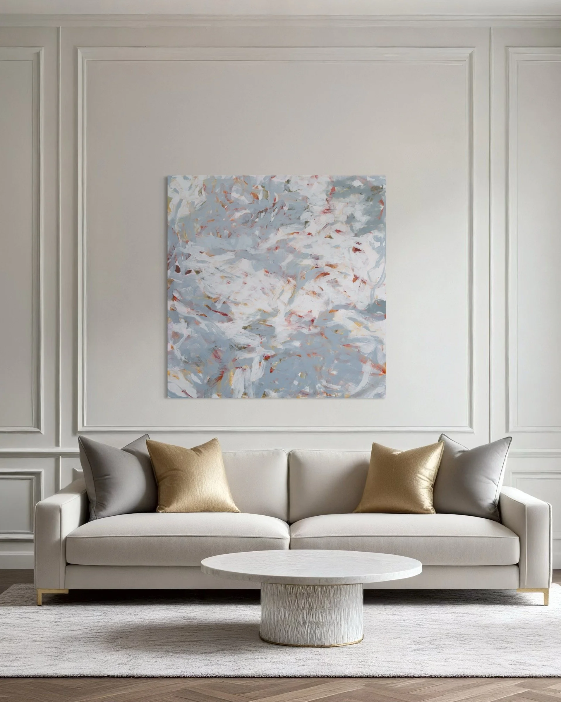 Elegant living room with a white sofa, gold and gray pillows, a textured white coffee table, and a large abstract painting on the wall.