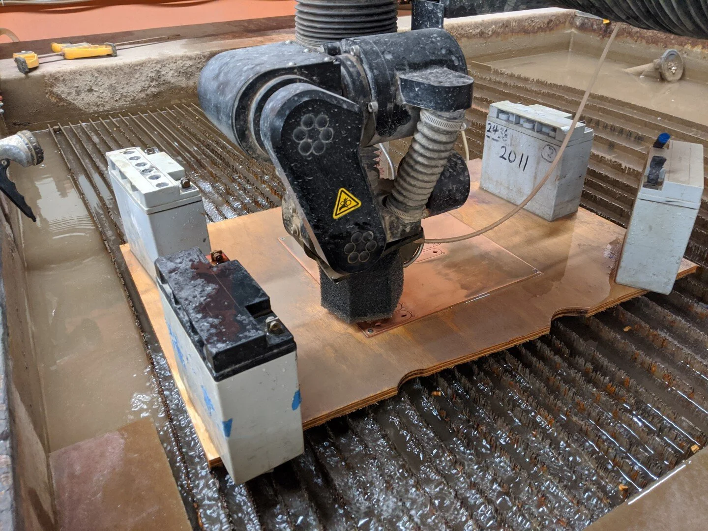 Using the waterjet to cut battery module connectors from copper plate.