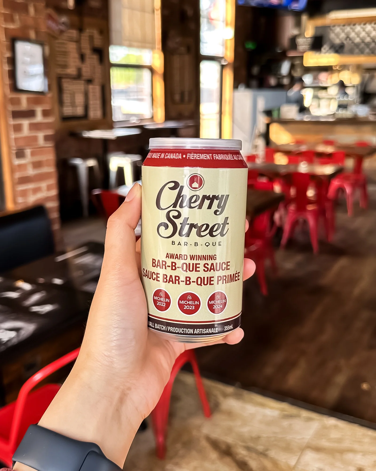 A can of Cherry St BBQ Sauce in hand