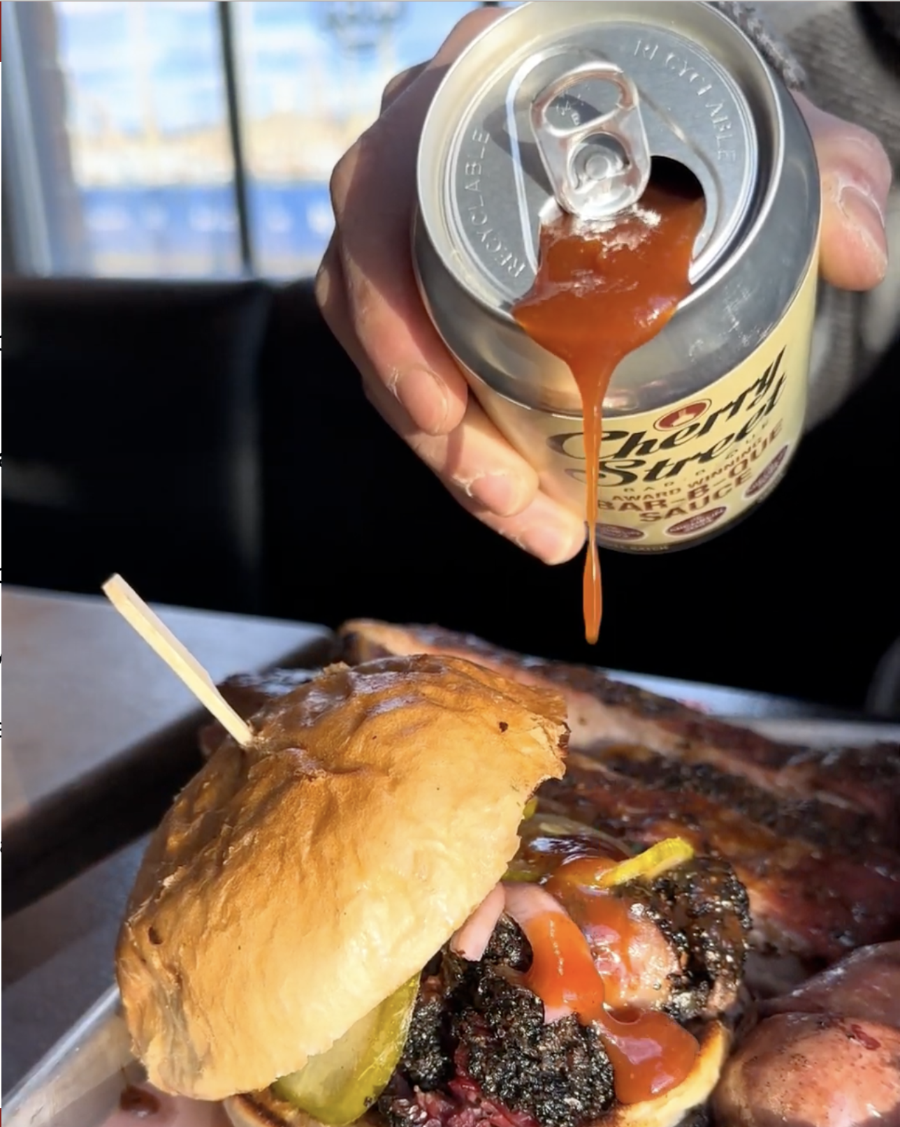 Cherry St BBQ Sauce being poured on sandwich