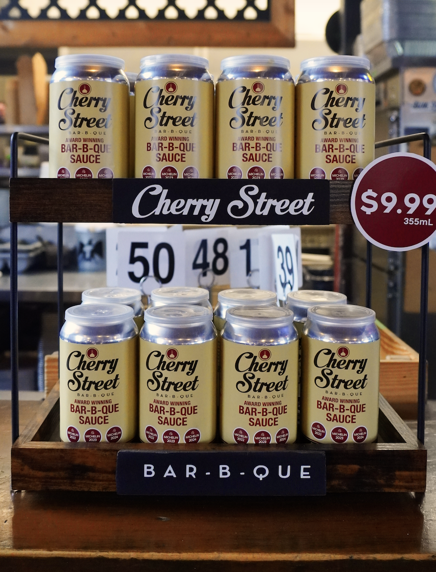 Cherry St BBQ Sauce cans aligned on display shelf
