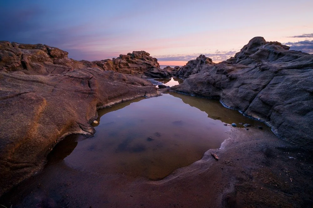 a rocky landscape with pink sky at sunrise on coast of Haida Gwaii
