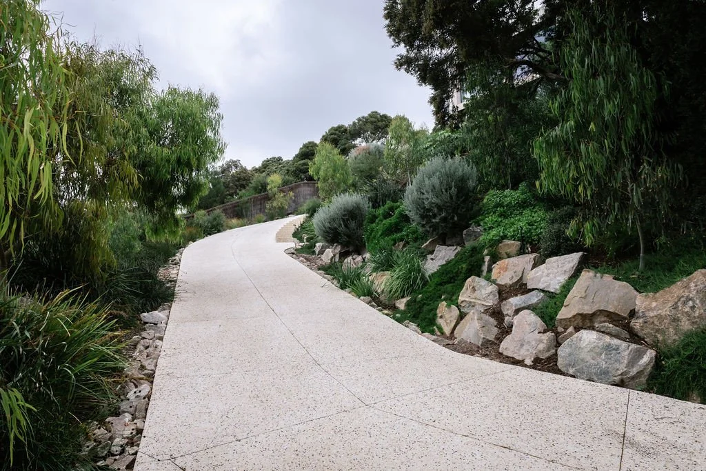 The driveway is the first element you encounter on this site.⁠
⁠
Exposed aggregate concrete curves with the natural fall of the land, while retention boulders step down alongside it.⁠
⁠
Landscape design @acre.landscape⁠
Concrete @rigzconcretepumping⁠