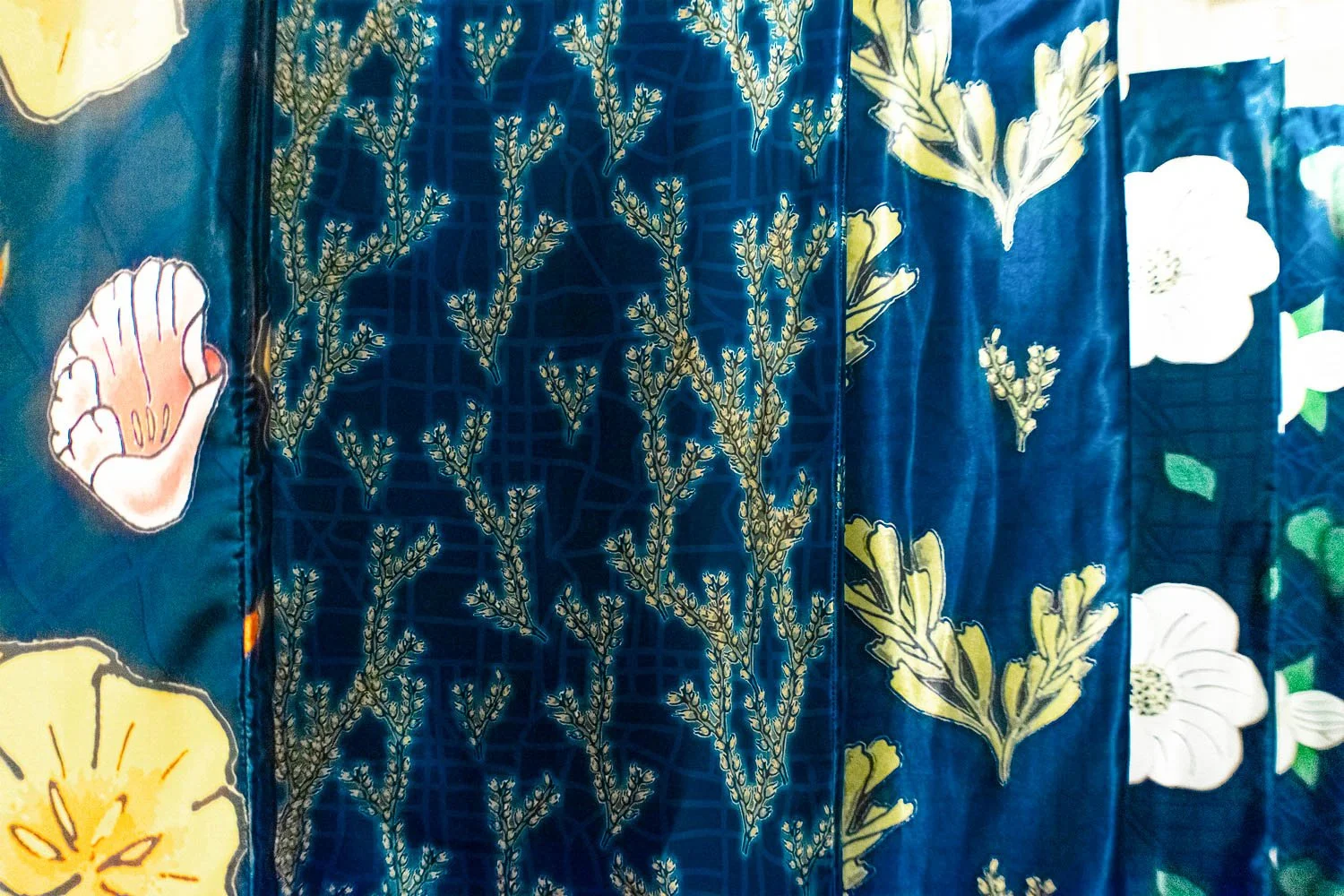 Close-up of floral patterned digitally printed hangings with botanical patterns featuring yellow and white flowers and green leaves on a blue background.