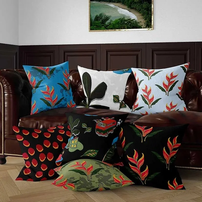 A brown leather tufted sofa with six colorful decorative pillows on and in front of it, featuring various floral and patterned designs. A framed landscape painting hangs on the wall above the sofa.
