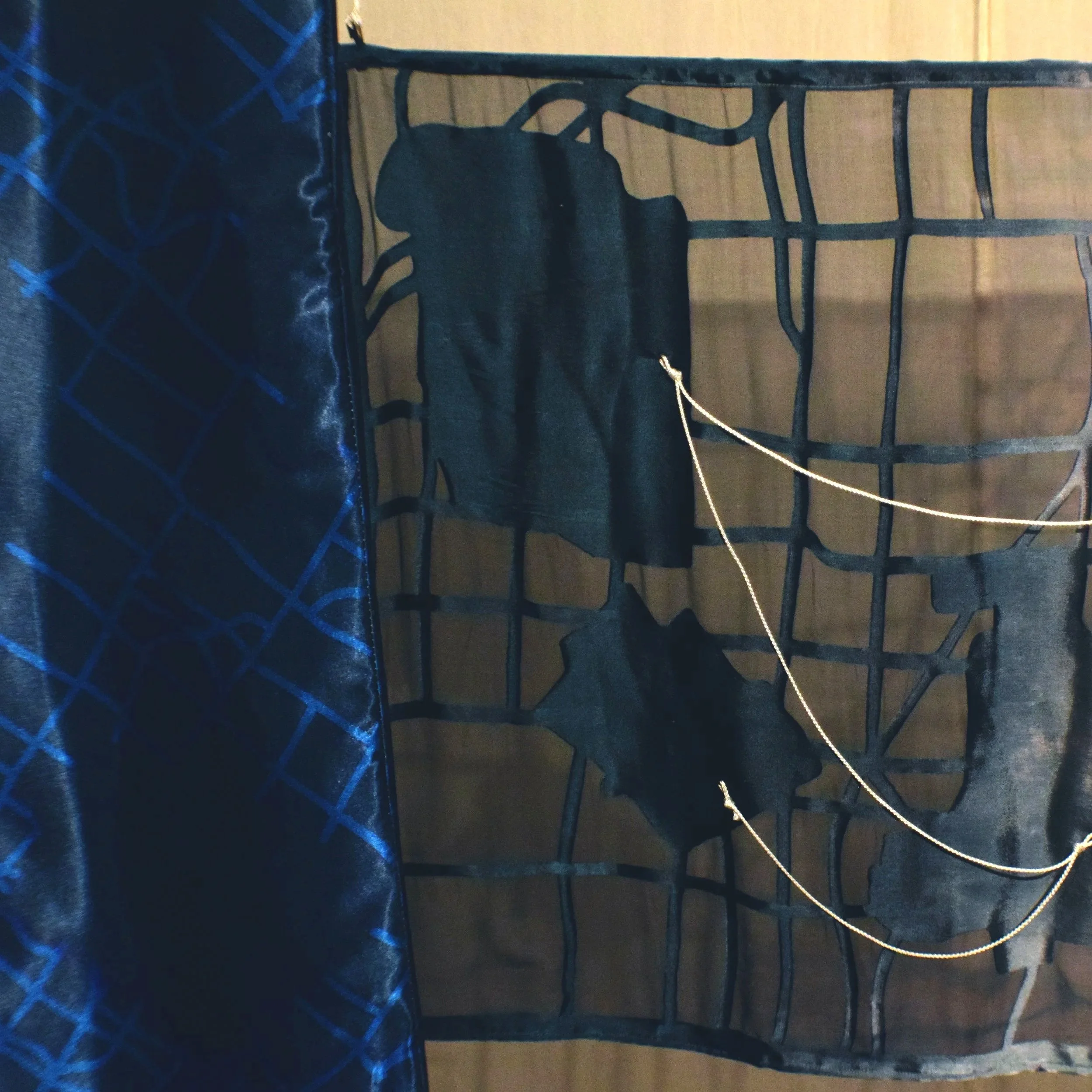 Detail close-up of horizontal burnout/ devoré wall hanging features one of the cities in the map, dyed deep blue, with cables leading to it.