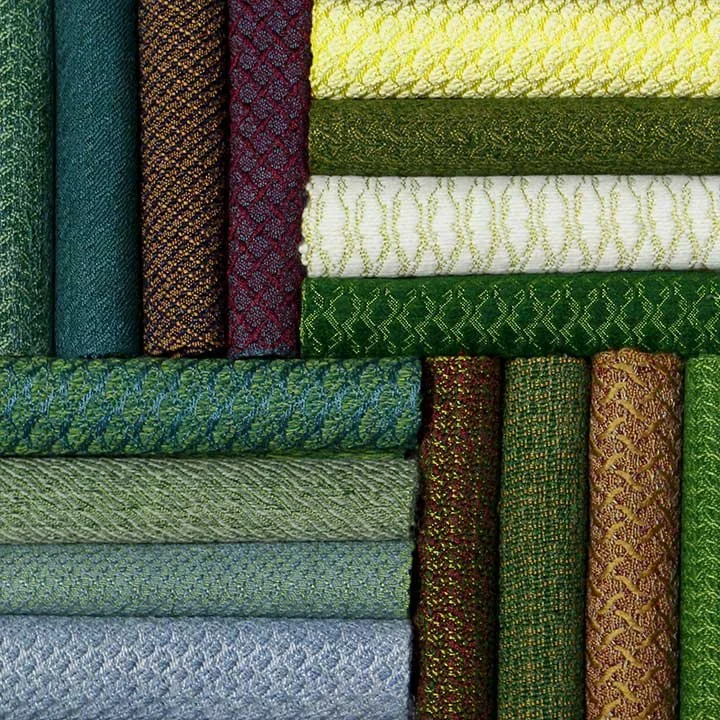 Stacked colorful woven fabric rolls in green, blue, yellow, white, red, and gold patterns.