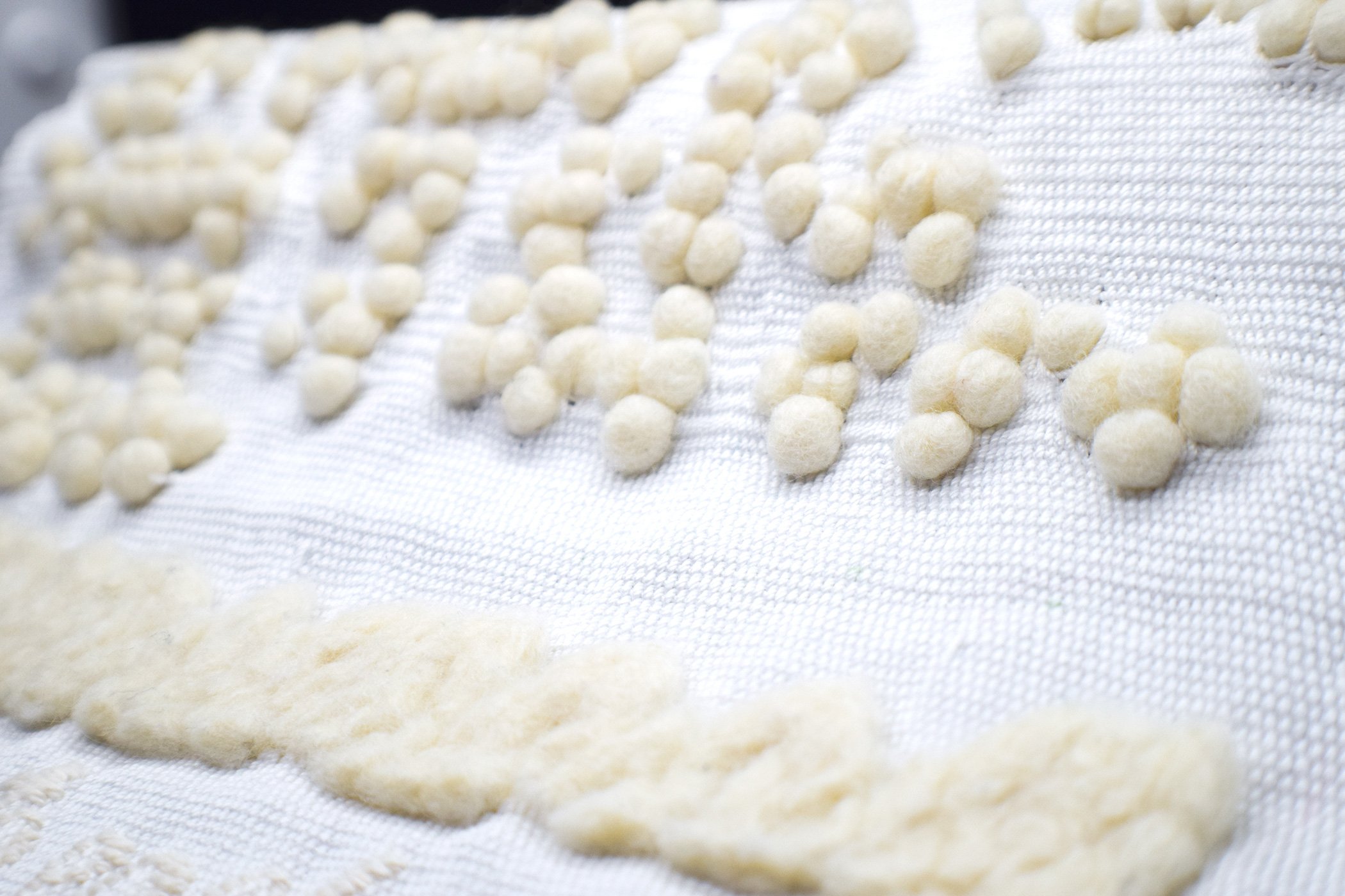 Felted braille in a white woven tapestry with an off-white felted wave beneath it