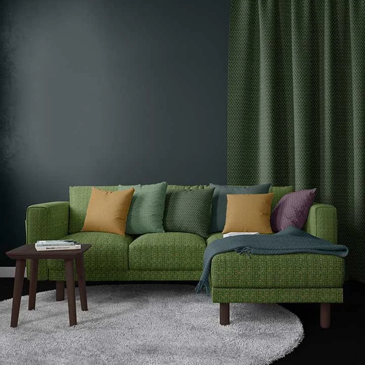Living room with a green sofa, multicolored pillows, a small side table with books, a dark green curtain, and a light gray rug.