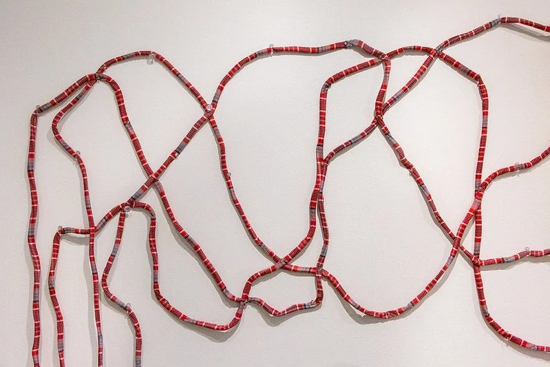 Detail of patchwork rope arranged in a loosely intertwined pattern against a white background.