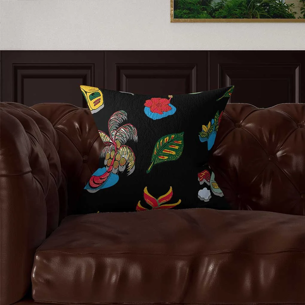 A decorative cushion with colorful embroidered floral and leaf patterns placed on a brown leather tufted sofa.