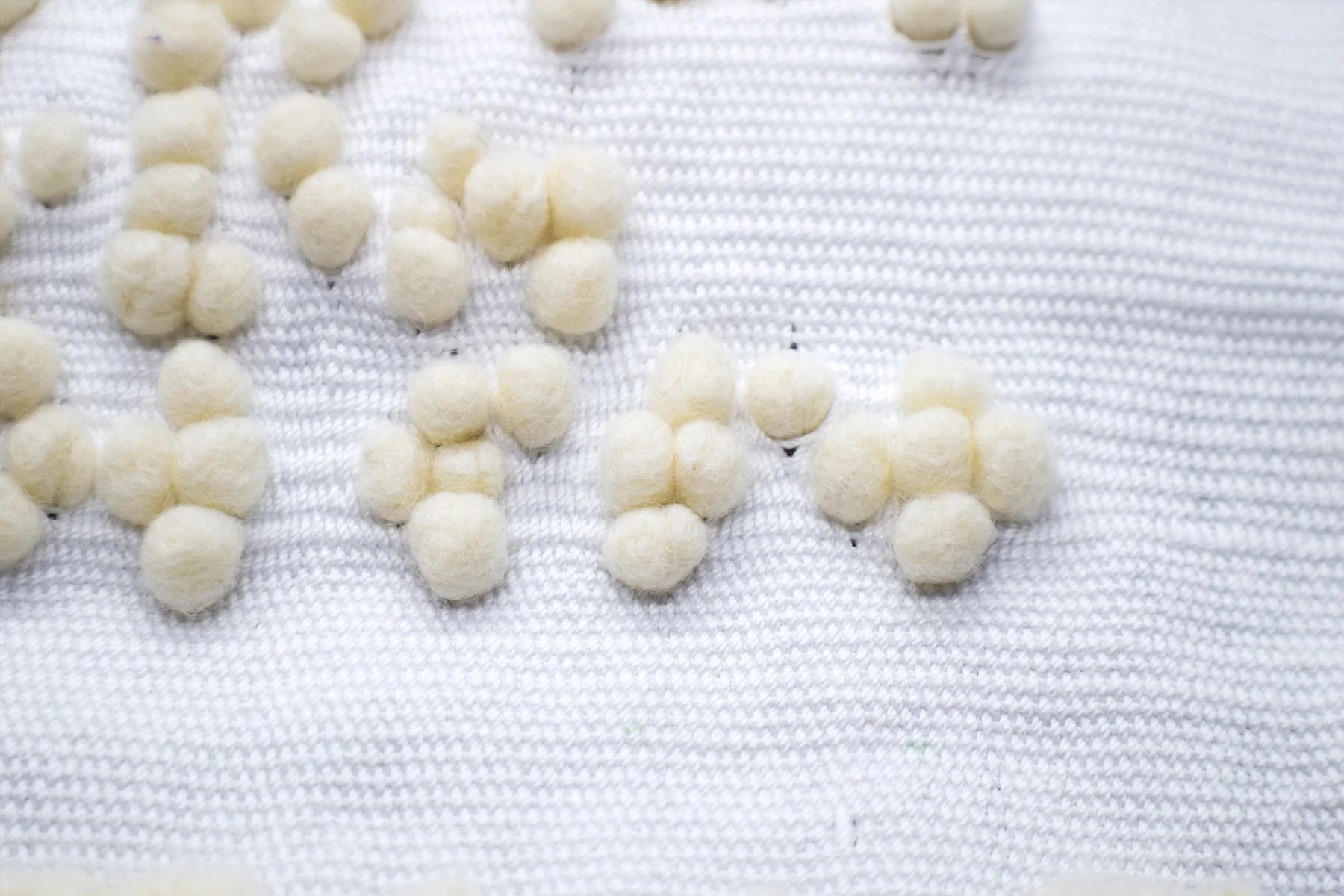 Close-up of felted braille on a white woven surface.