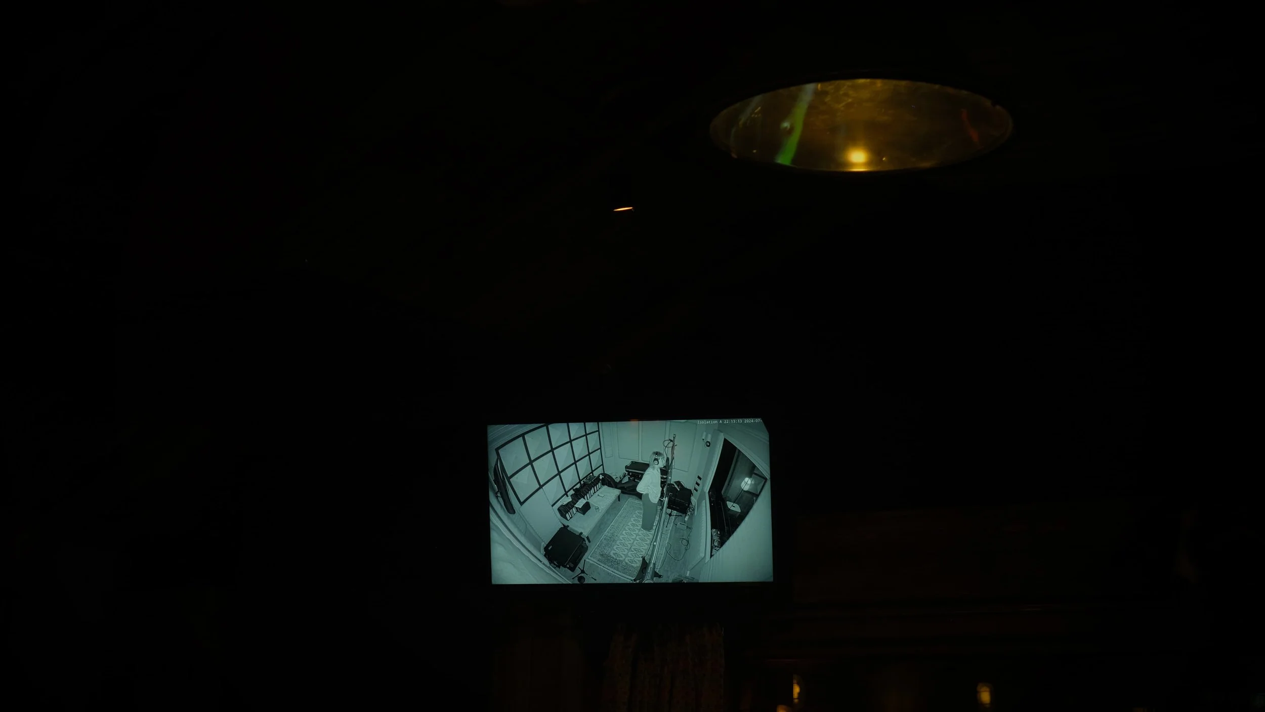 Surveillance camera shows a person in a small room with a door, some furniture, and equipment.