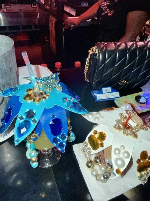 Decorative masquerade masks adorned with pearls, rhinestones, and gold accents on a table in a dimly lit setting.