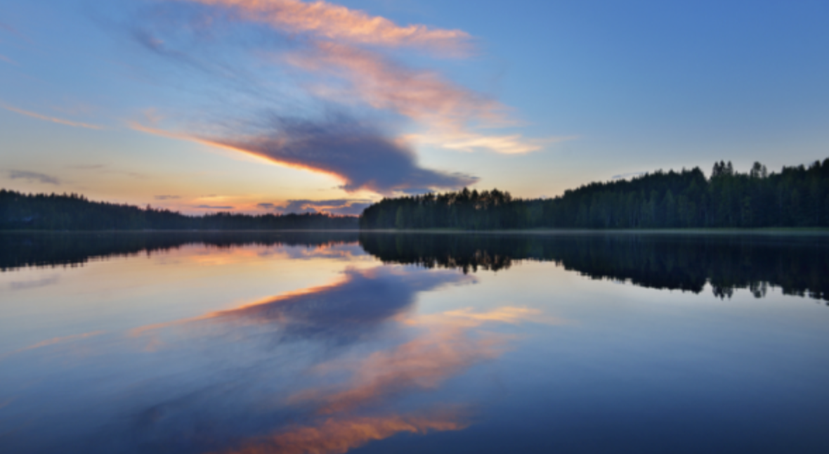 Image of sunset on a lake with pink clouds reflected in the water.