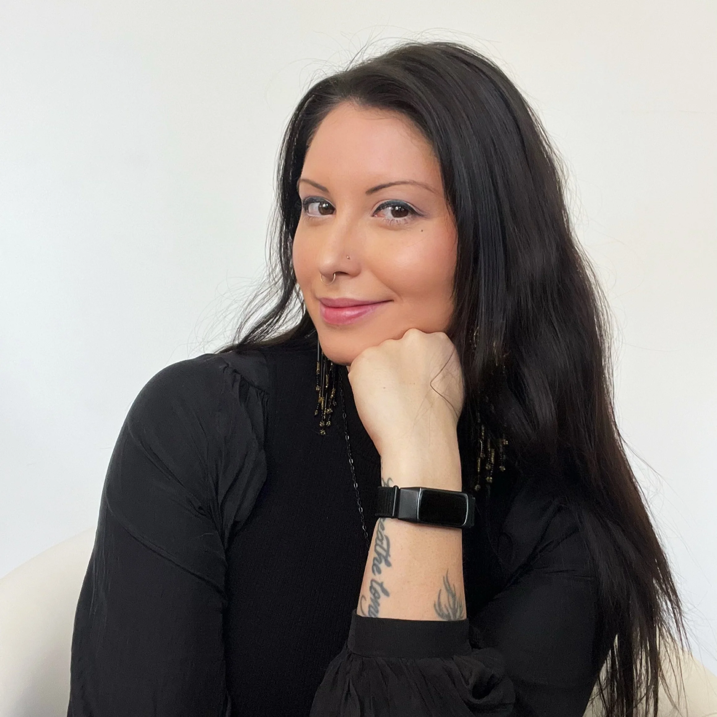 a women with black hair holding her hand to her chin 