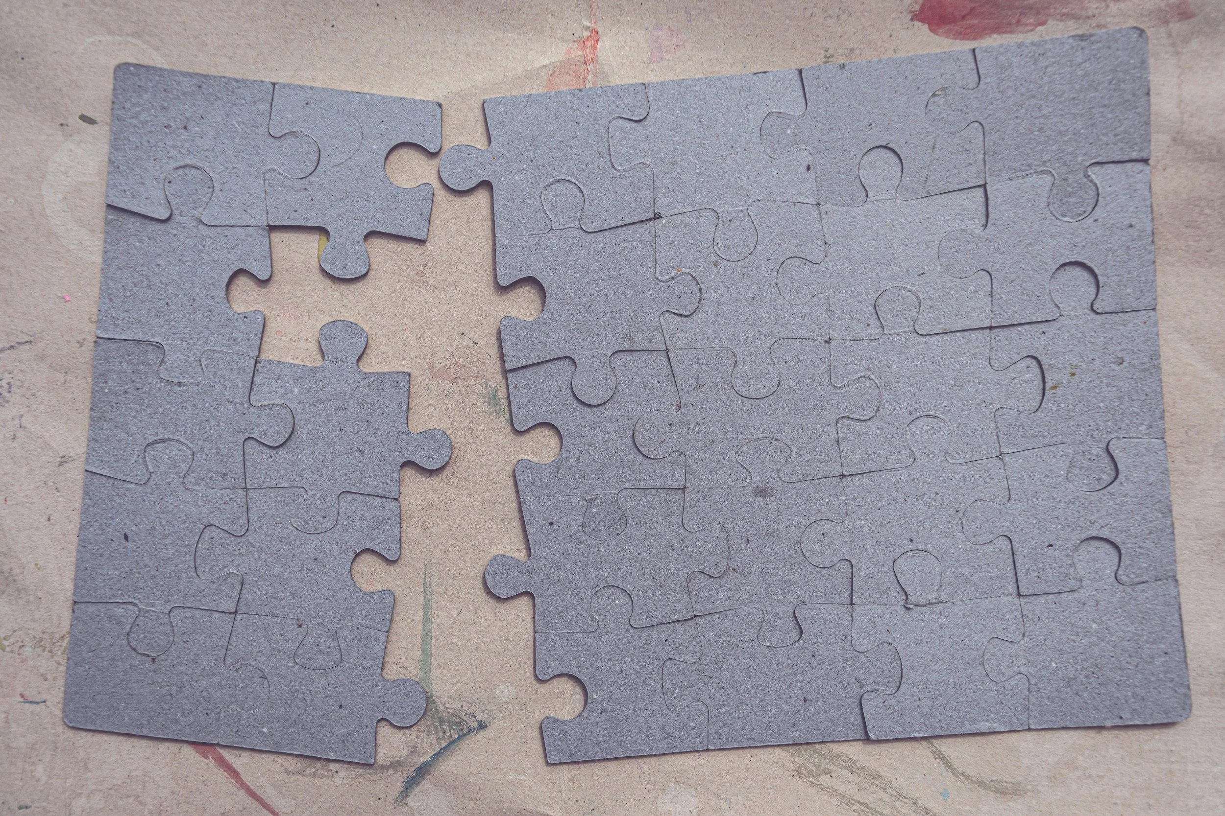 Gray puzzle pieces assembled on a surface with a few pieces missing.