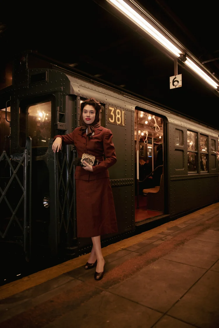 People in vintage clothing inside a vintage subway car