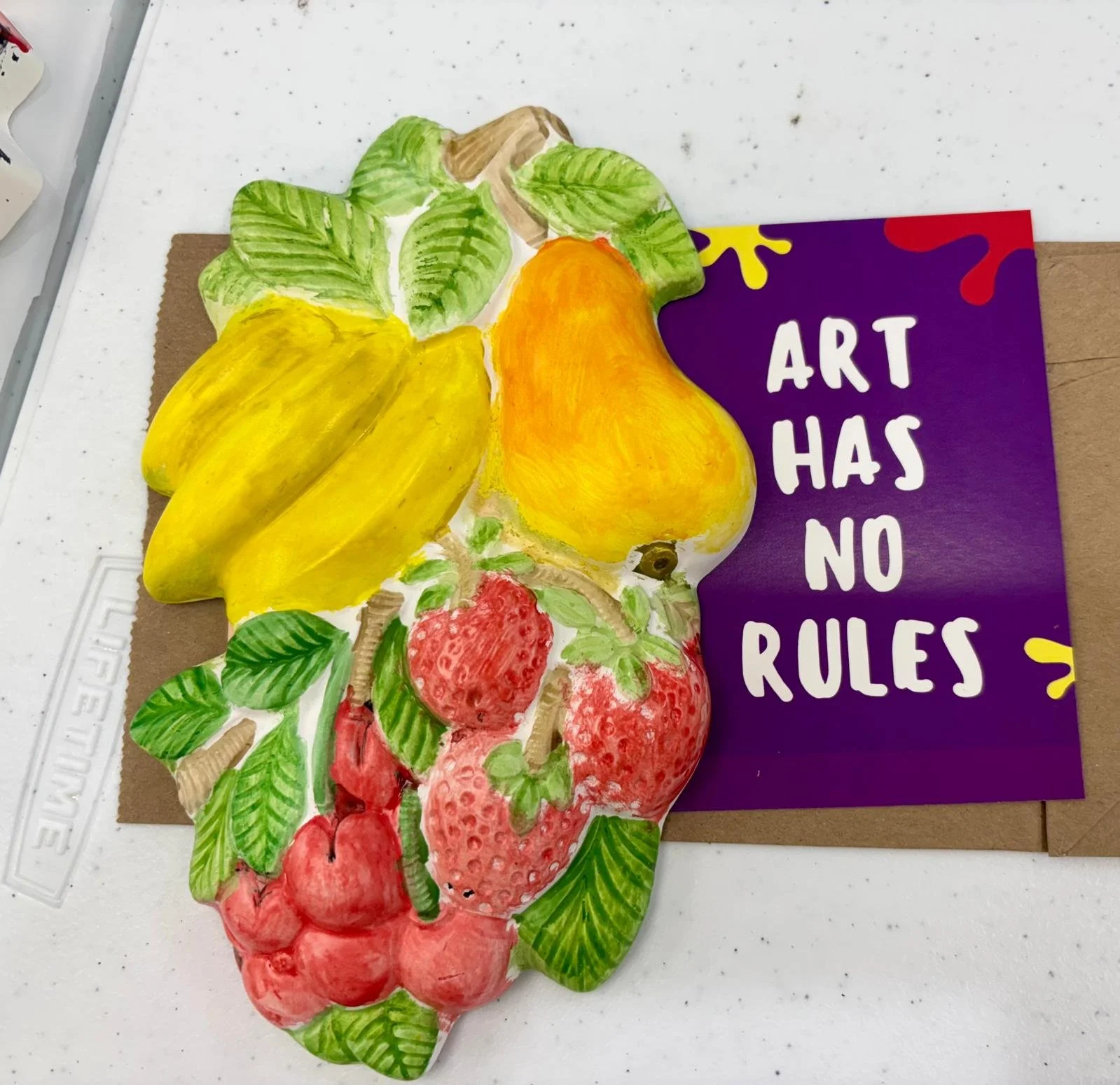 Flat lay of a children's craft project with various objects arranged on a blue fabric background, including a cutout of a blue truck, buttons, pipe cleaners, and star-shaped cookie cutters.