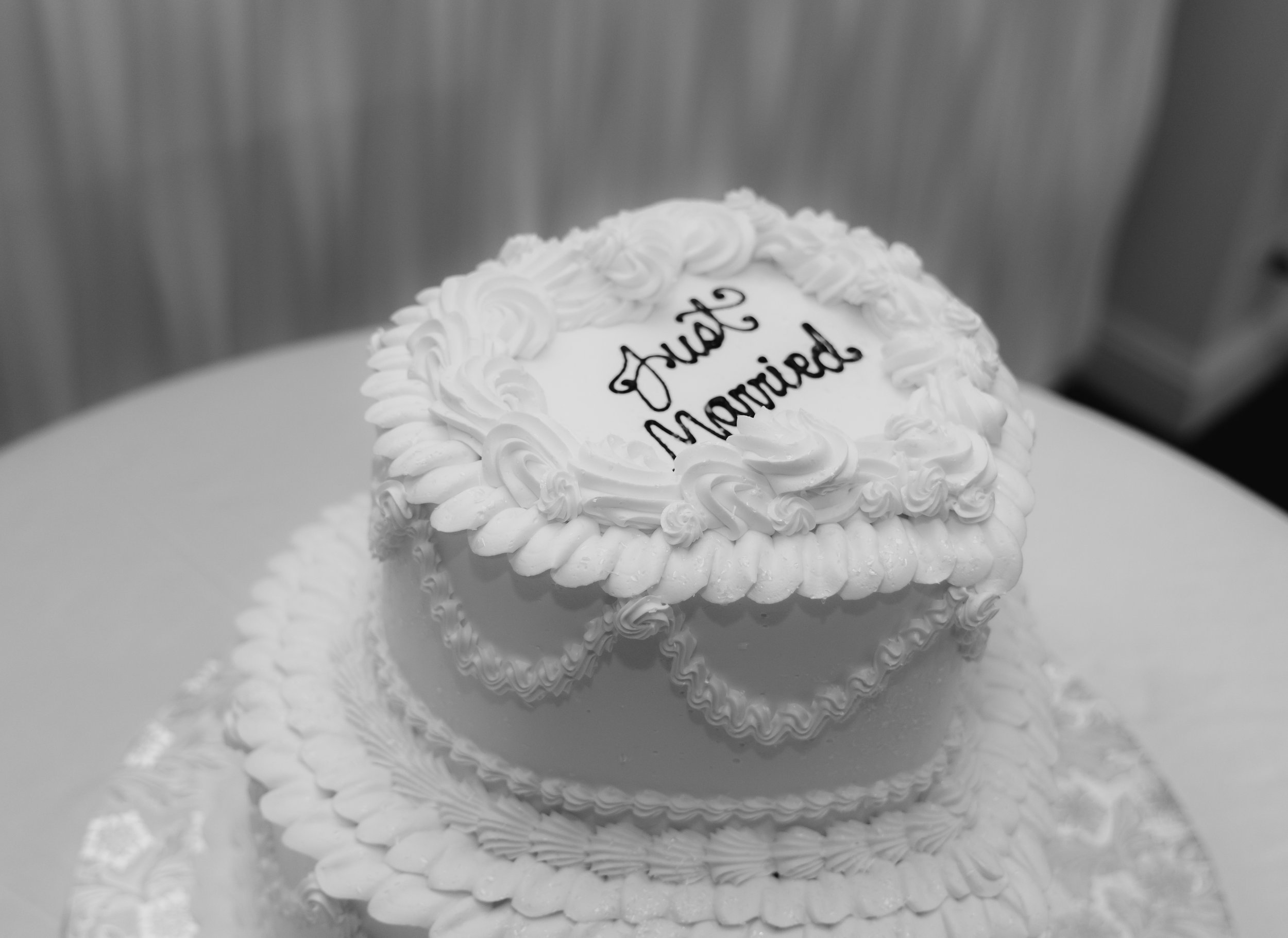 A wedding cake with a heart-shaped top layer featuring the words "Just Married" written in black icing.