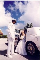 A man and a girl dressed in white standing near a white car outdoors.