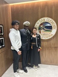 Three people posing in front of a sign that says 'City of San Clemente, California.'