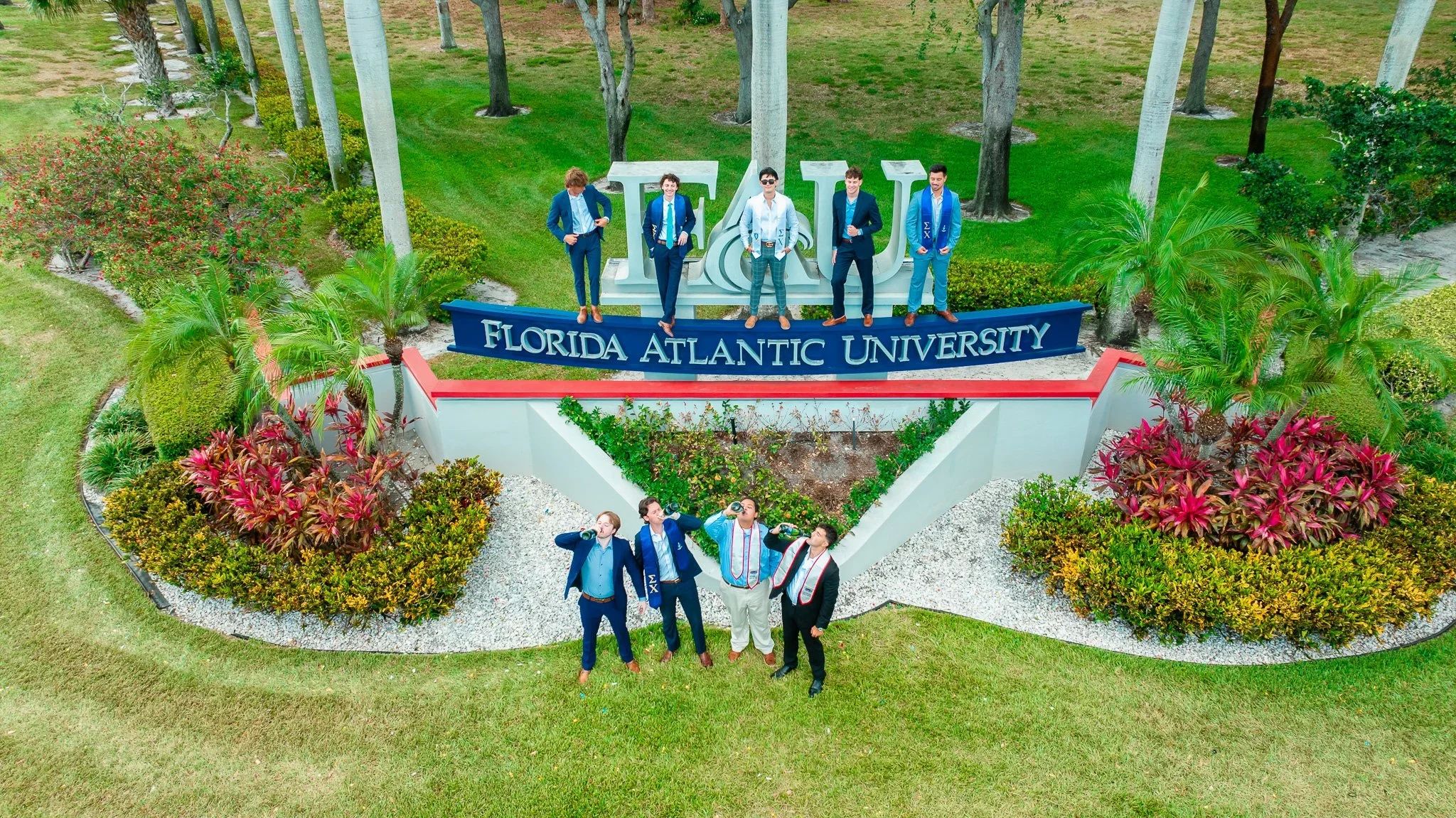 Drone view of graduates and friends celebrating around the Florida Atlantic University entrance sign