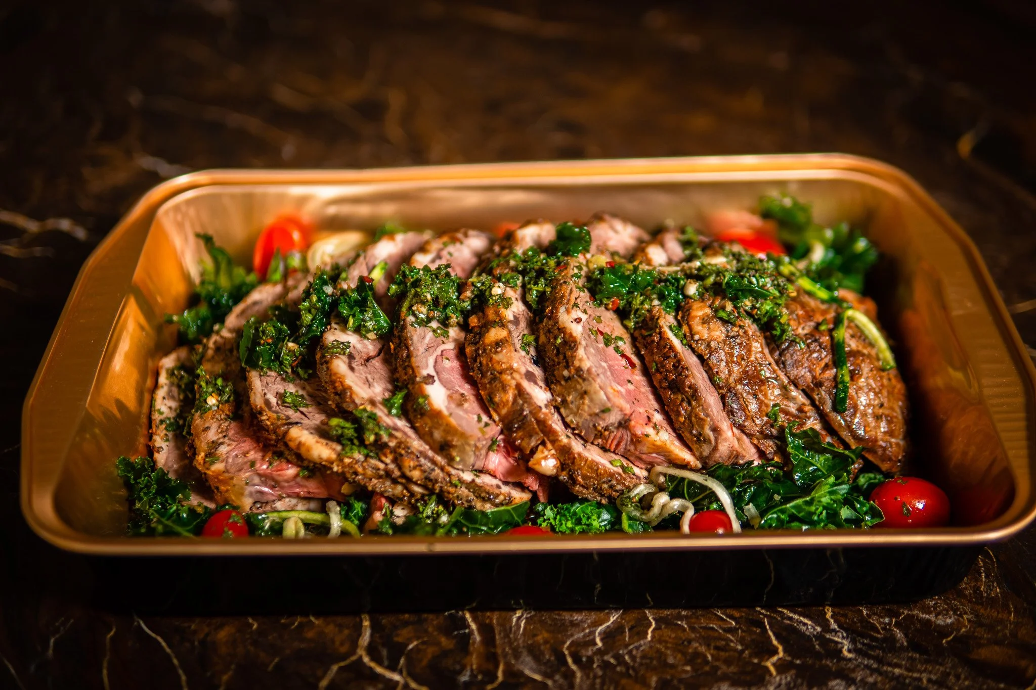 Sliced roast served with vegetables and fresh herbs