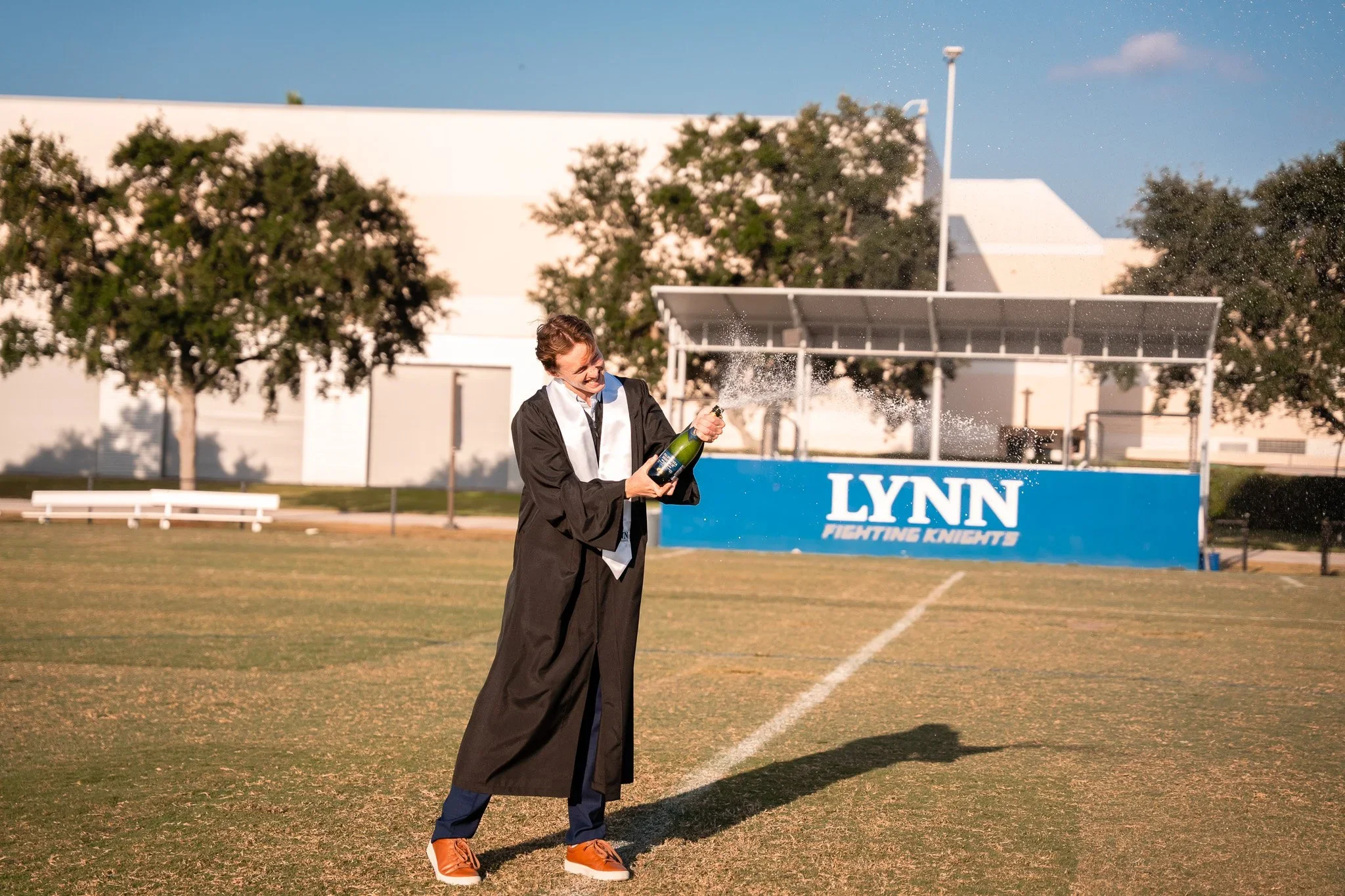 Cameron spraying champagne on the Lynn University athletics field after graduation