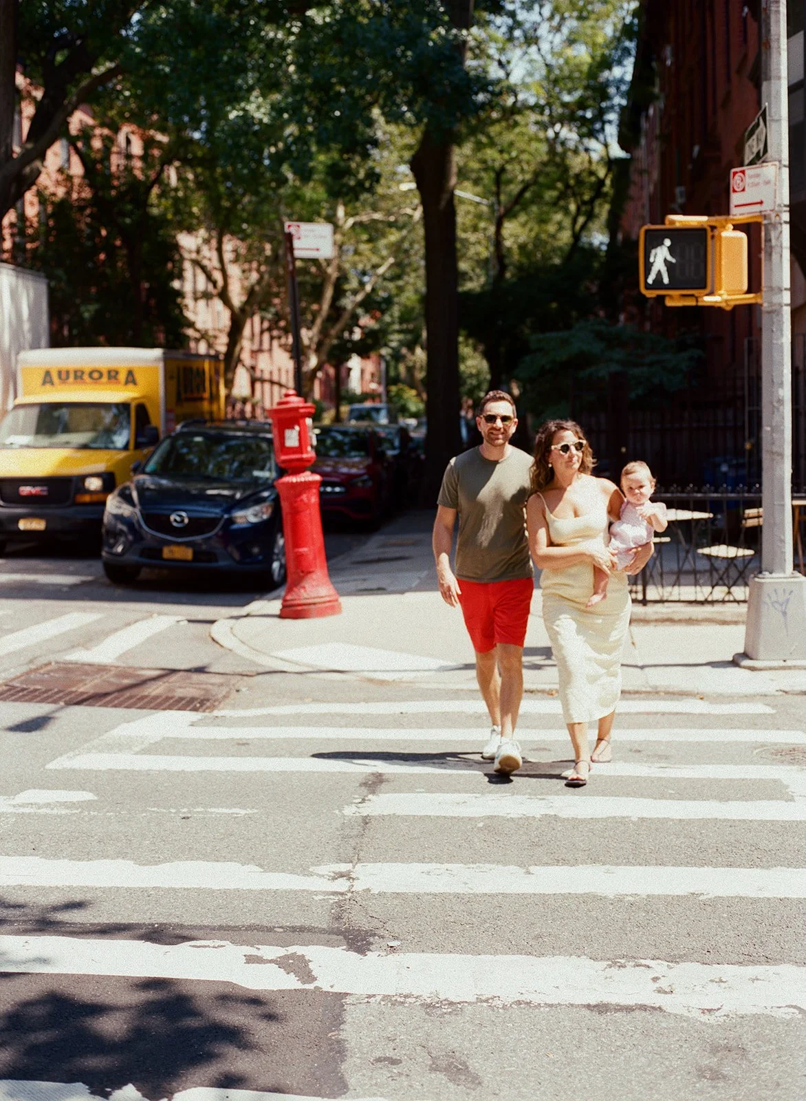 A couple carrying an infant child cross an intersection in NYC during their family photo session.